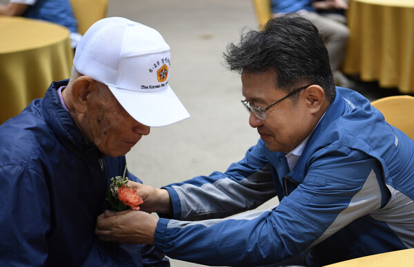 한성희 포스코이앤씨 사장이 참전 유공자에게 꽃을 달아드리고 있다. [사진=포스코이앤씨 제공]